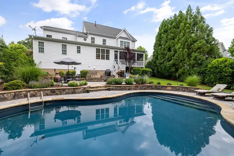 Backyard swimming pool with clear water behind a two-story home
