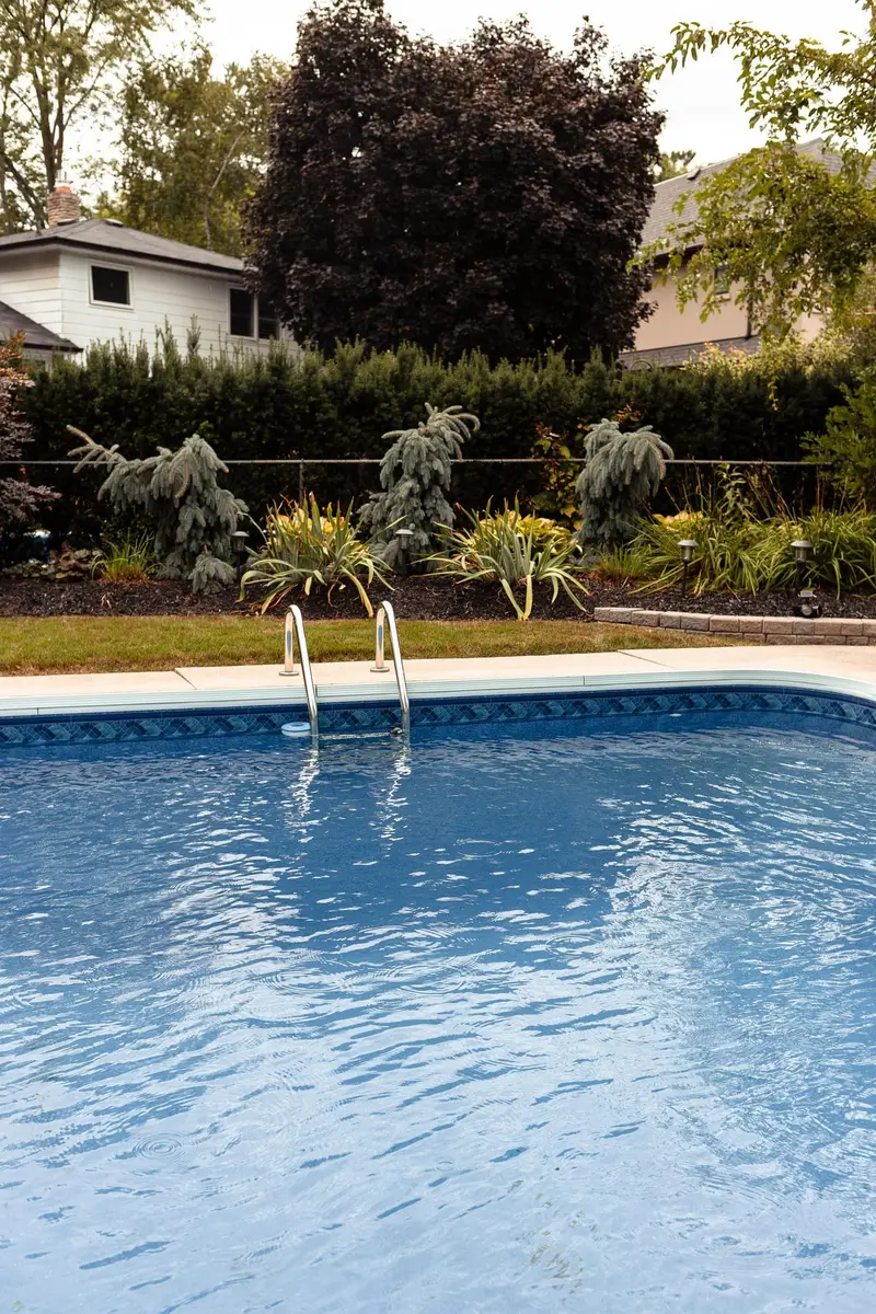 Backyard pool with clear blue water and a landscaped yard