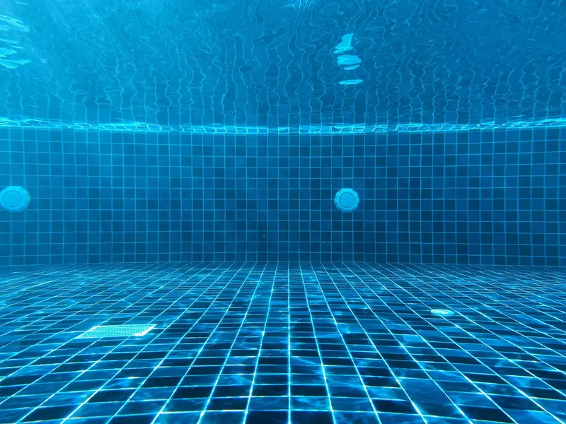 Underwater view of blue pool tile and a floor drain